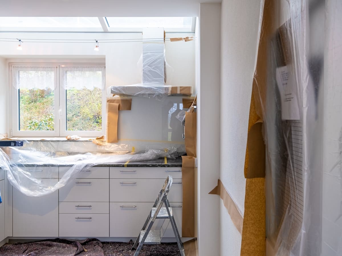 A kitchen mid-refurbishment, units unfitted and dust sheets down